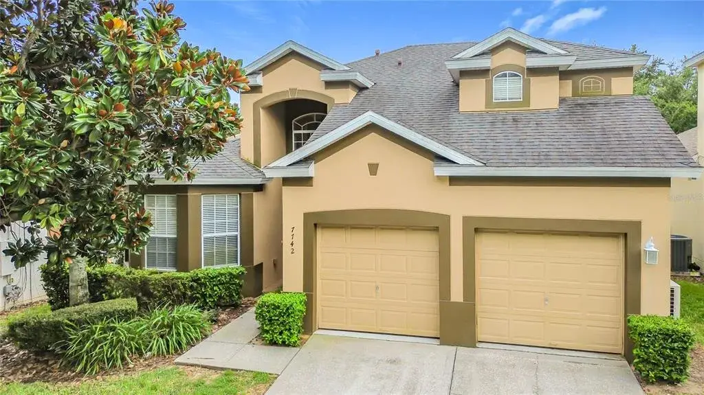 Beautiful front elevation with mature landscaping and a two-car garage.
