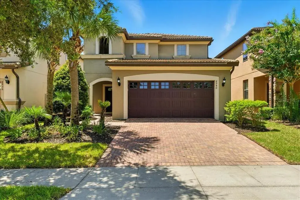 Tropical escape vibes from the moment you arrive — swaying palms, sun-kissed exterior, and a paver driveway that says welcome to vacation.