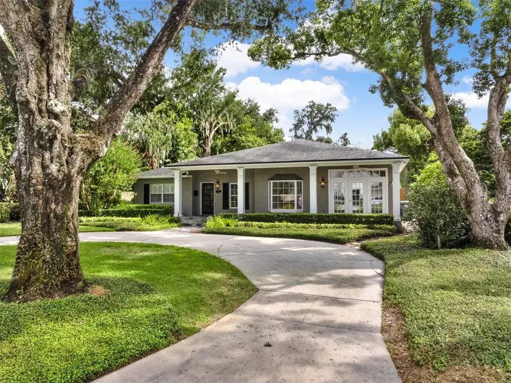 Inviting single-story residence with a welcoming front porch, classic columns, and mature landscaping. A circular driveway enhances both curb appeal and functionality.