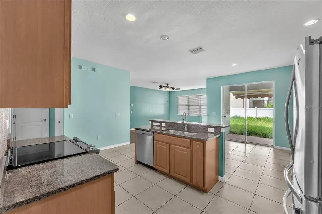 Stainless Steel Built-in microwave, glass-top range, side-by-side refrigerator, dishwasher and sink in island.