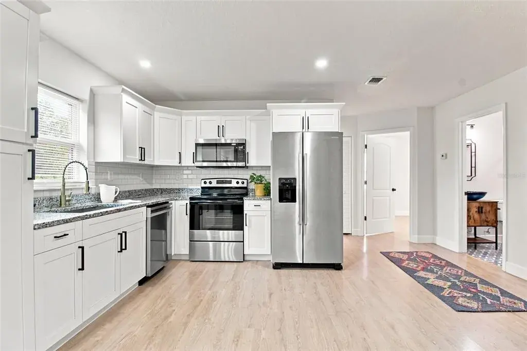 View from living area to light and bright kitchen, and hallway leading to second bathroom and all of the bedrooms