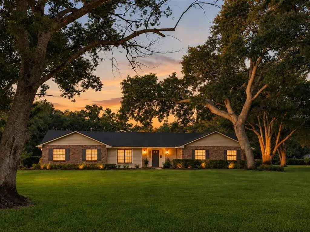 Twilight view of this beautiful pool home on over an acre of land with mature trees.