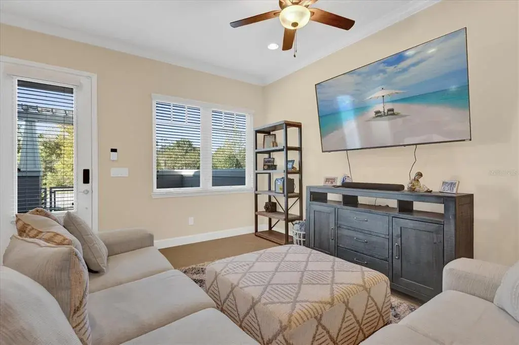 Cozy sitting area with ceiling fan and natural light, offering flexible living space.