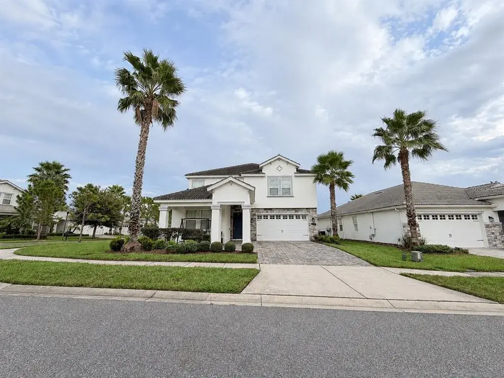 Inviting front elevation featuring a covered porch, stone accents and paver driveway.