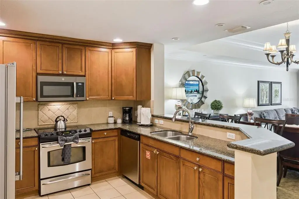 Fully Equipped Kitchen: Modern kitchen featuring warm wood cabinets, tile backsplash, granite counters, and full stainless steel appliances including a built-in microwave and range.