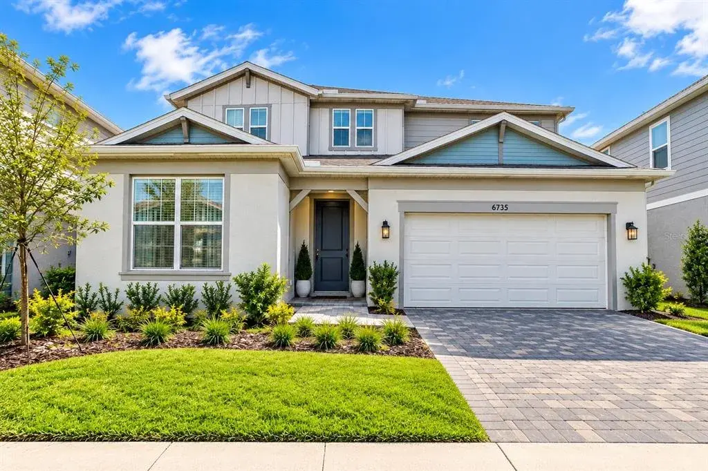 Beautiful two-story home featuring modern architectural details, a two-car garage, paver driveway, and professionally landscaped front yard.