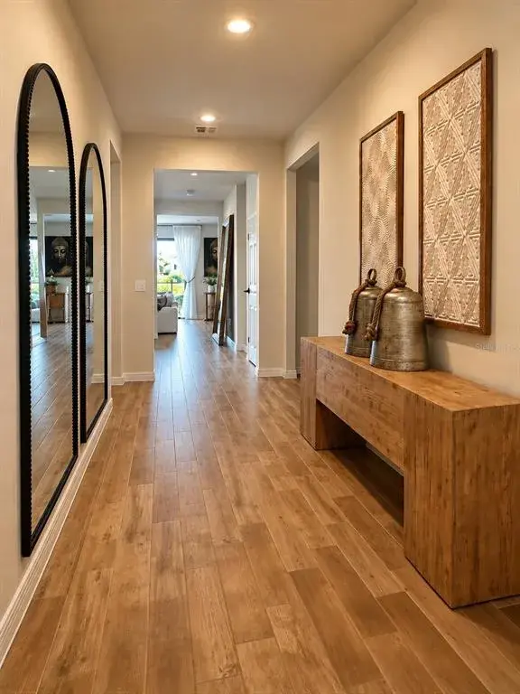 Welcoming foyer with warm wood-look flooring, recessed lighting, and a spacious hallway leading into the main living areas