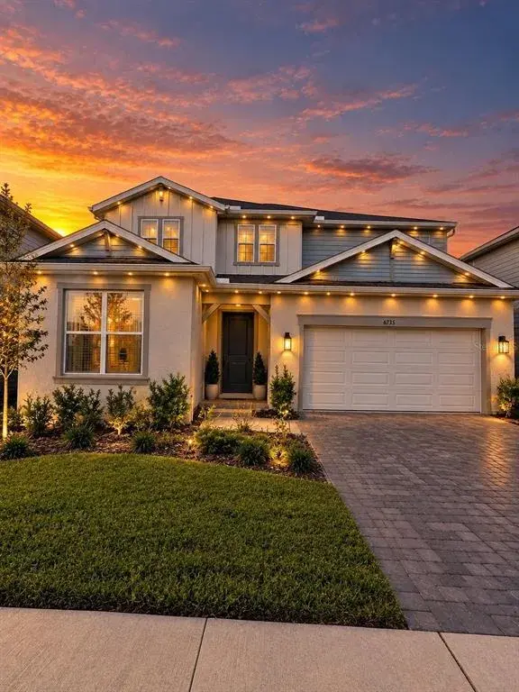 Stunning two-story home featuring beautiful architectural details, elegant exterior lighting, a paver driveway, and exceptional curb appeal.