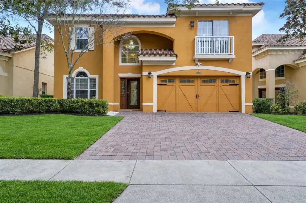 A brick paver driveway leading to a spacious two-car garage with decorative carriage-style doors and black hardware accents.