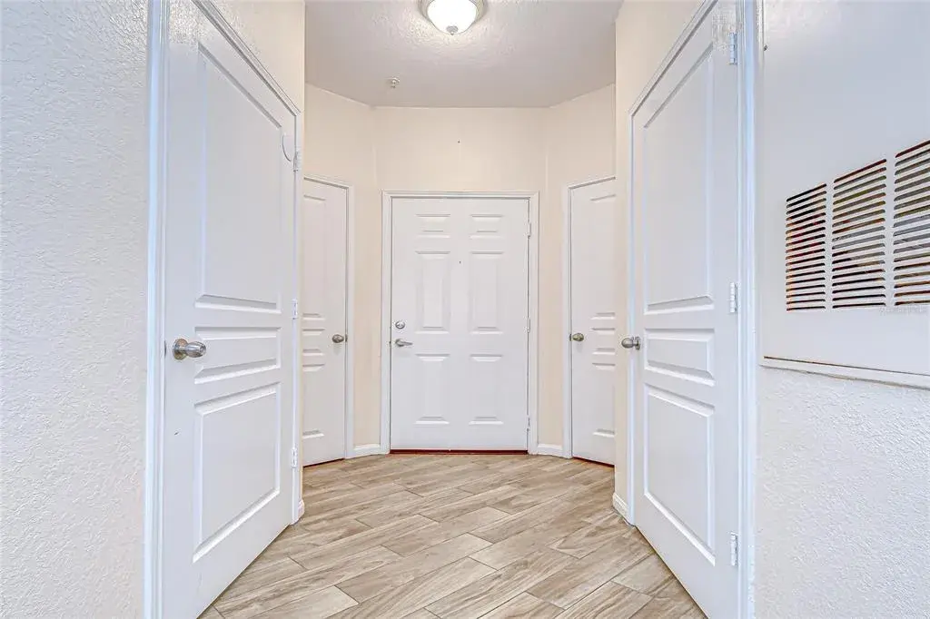 Bright and functional foyer features wood-look flooring, multiple surrounding storage or utility closets, and an open entryway leading into the main living areas.
