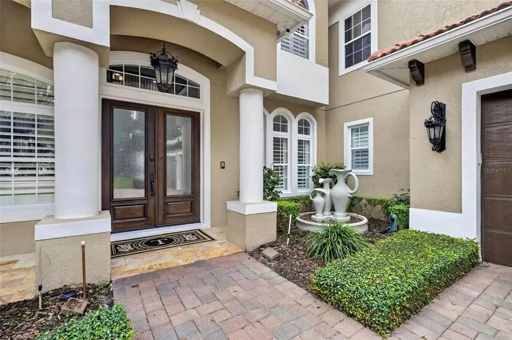 Welcoming front entry surrounded by mature landscaping and Mediterranean-inspired details.