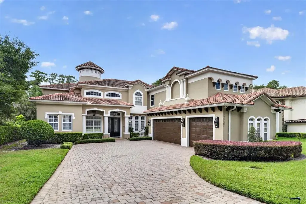 Front exterior of this two-story Mediterranean lakefront residence with three-car garage and circular drive.