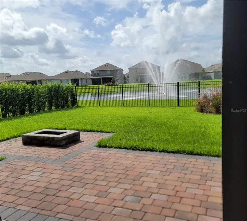 Private Fenced Yard with extended pavers, firepit, privacy bushes, and water view overlooking beautiful fountain