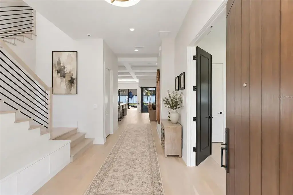 Entryway into the home with built in storage bench to the left and guest bedroom with double doors to the right