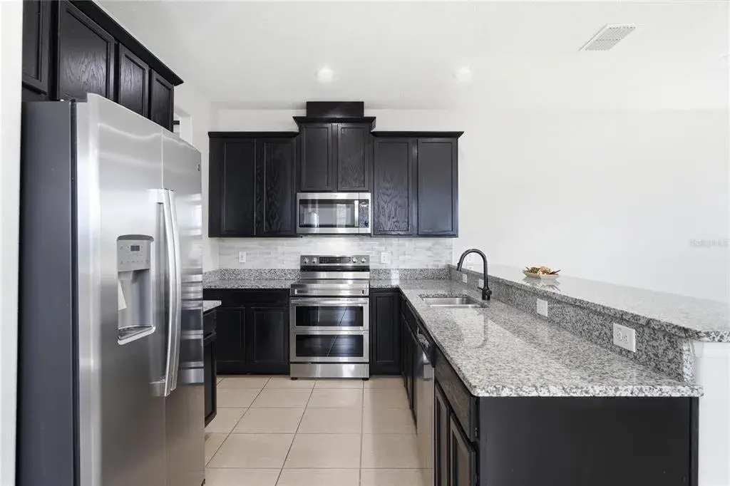 Open kitchen featuring granite countertops, stainless steel appliances and abundant cabinetry.