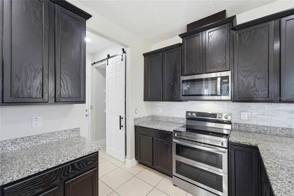 Stylish kitchen with granite countertops, subway-tile backsplash, abundant cabinetry and stainless steel appliances.