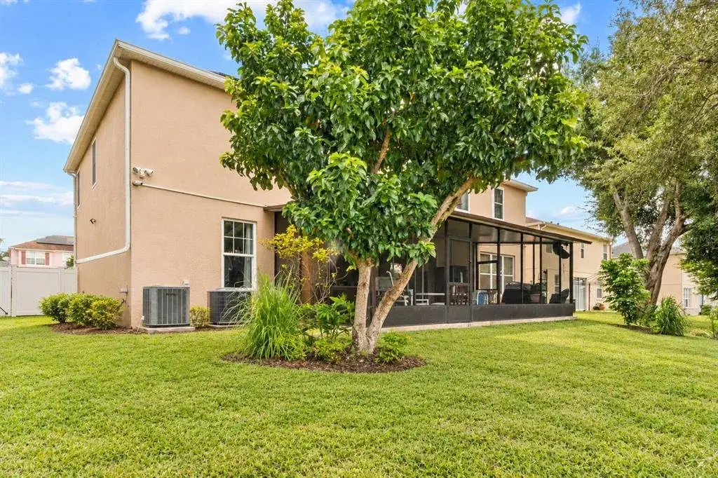 Rear exterior view with a spacious backyard and mature landscaping.