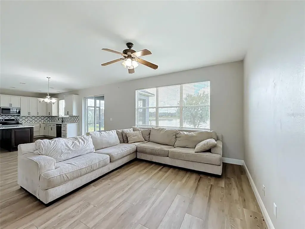 Living room open to the kitchen with wood-look flooring