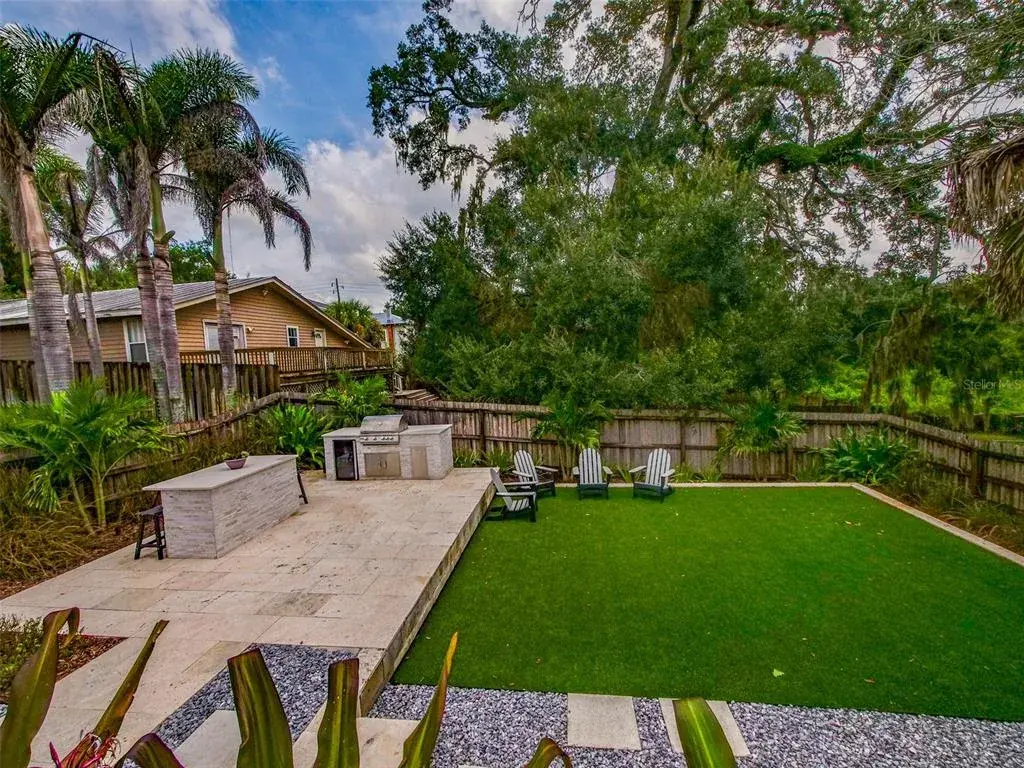 Backyard with outdoor kitchen, turf, and mature tree canopy
