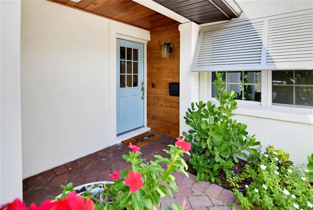 Welcoming covered front entry with attractive architectural details and lush landscaping.