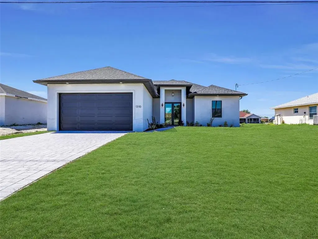 Contemporary stucco exterior with a dark garage door and a contrasting paver drivewaythe color of the grass has been virtually enhanced