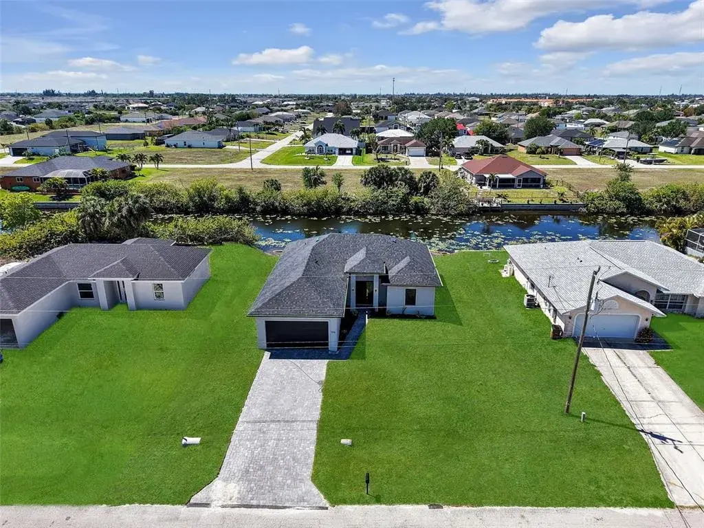 Newly constructed residence featuring a dark shingle roof, paver driveway, and a spacious lawn the color of the grass has been virtually enhanced