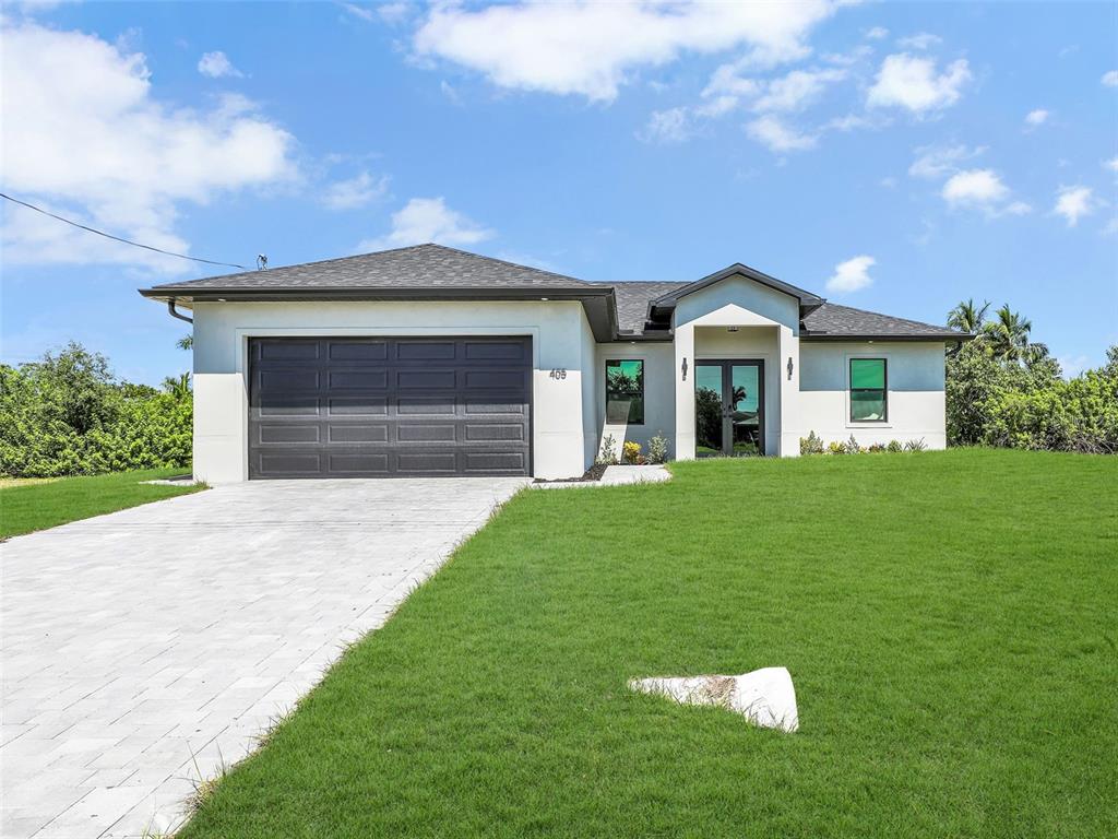 Front of house with stucco siding, a front yard and a decorative driveway
