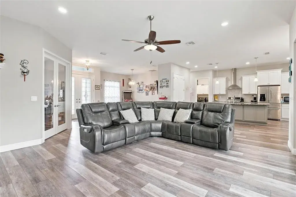 Open Floor Plan-Living Room overlooks Kitchen featuring laminate wood flooring, sliders to screened lanai.