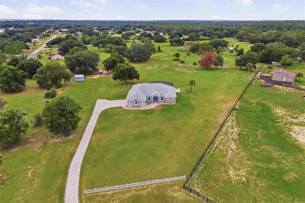 Aerial-Exterior front of home. Situated on Just under 5 acres of land, brick paver drive, and heated salt water screen enclosed swimming pool.