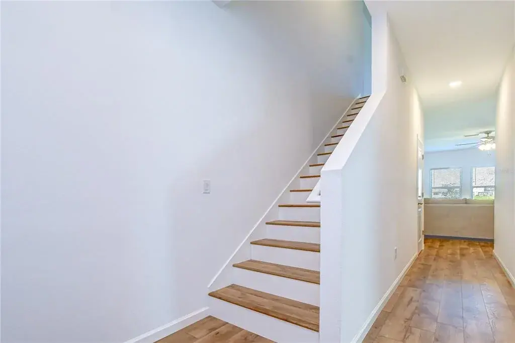 Bright and welcoming foyer featuring an open-concept layout and an elegant staircase leading to the upper level.