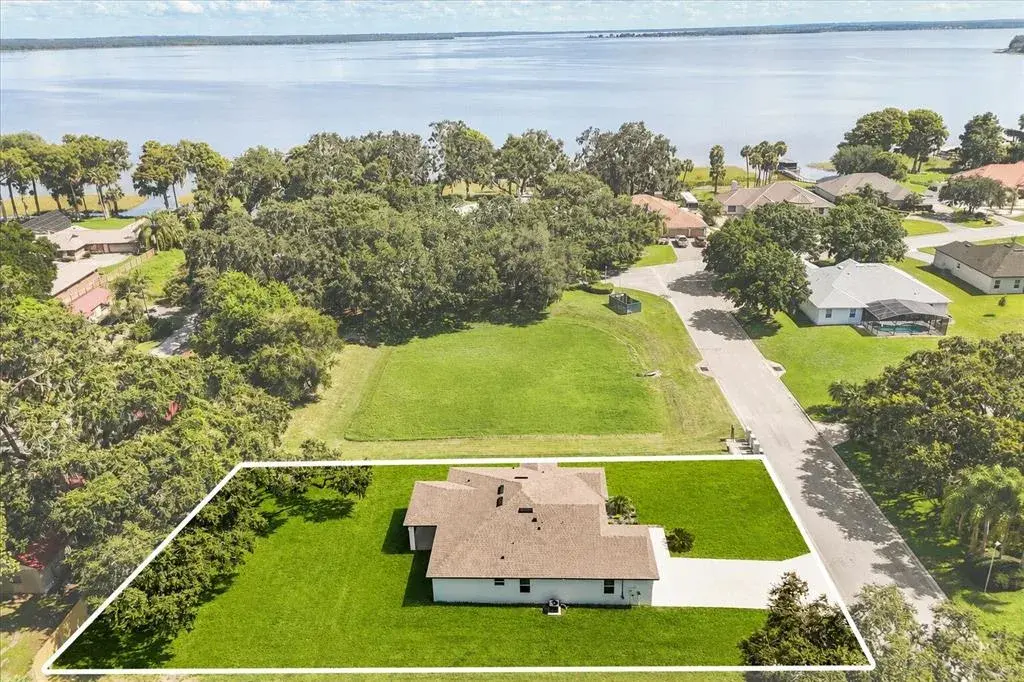 Aerial view showcasing the premium lot, added privacy with no neighboring home on one side, and partial lake views from the backyard