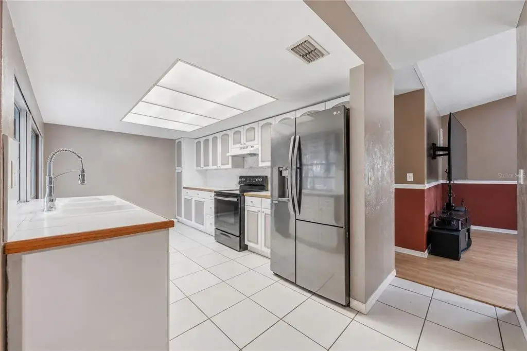 Functional galley kitchen with stainless steel appliances, tile flooring, generous counter space, and seamless view into the adjacent living space.