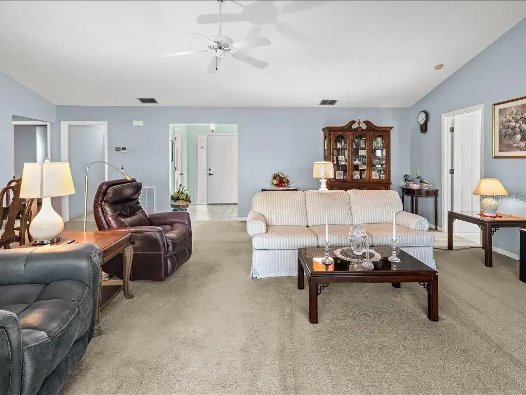 VIEW OF THE LIVING ROOM TOWARDS THE FOYER. THE PRIMARY BEDROOM IS ON THE RIGHT AND THE 2ND BEDROOM, LAUNDRY AND GUEST BATH ARE ACCESSIBLE TO THE LEFT.