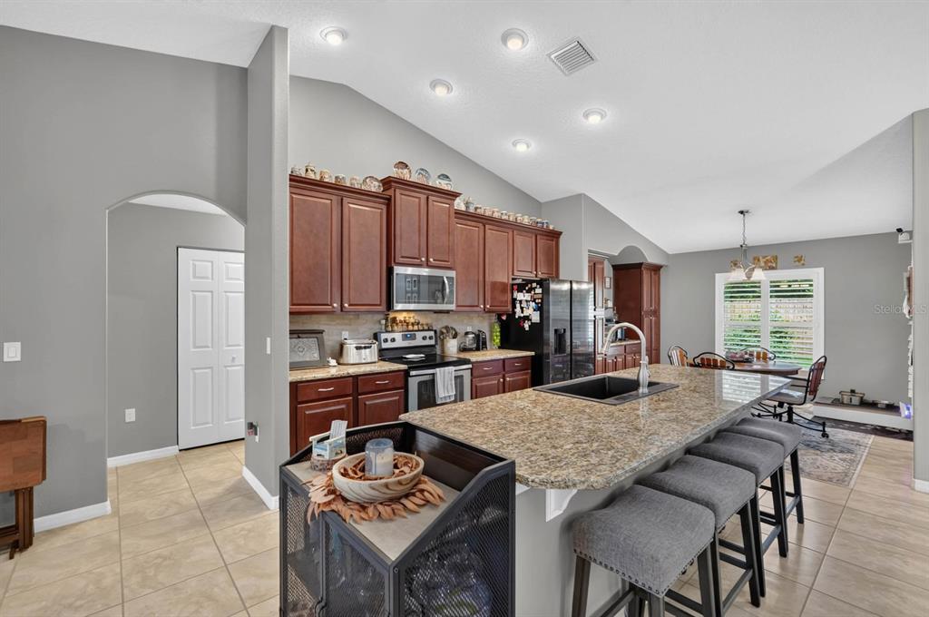 Kitchen features stacked wood cabinetry, granite countertops, large island