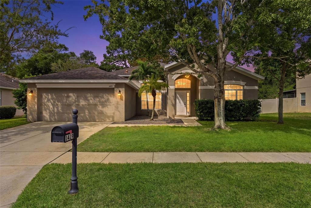 A warm twilight view highlights the home’s inviting entry and established neighborhood setting.