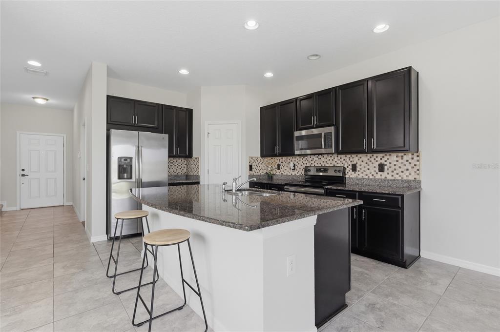 Modern kitchen featuring dark wood cabinetry, granite counters, and a spacious center island