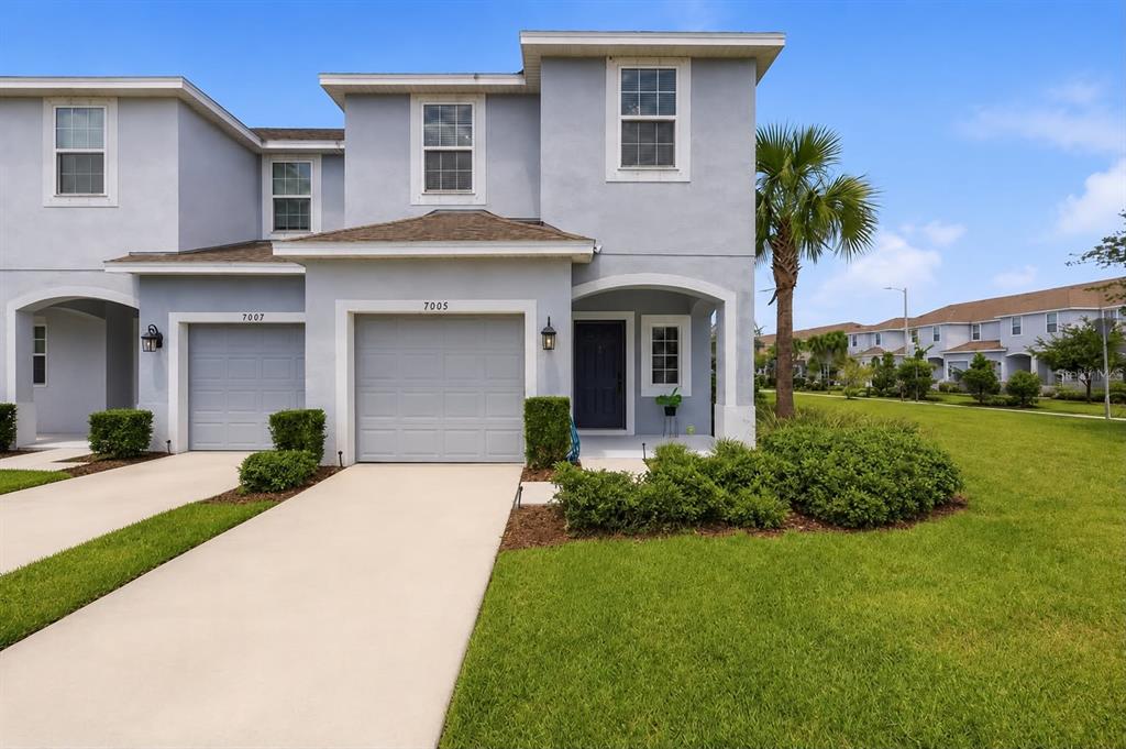 Beautiful front elevation with two-story facade, covered entry, and manicured landscaping