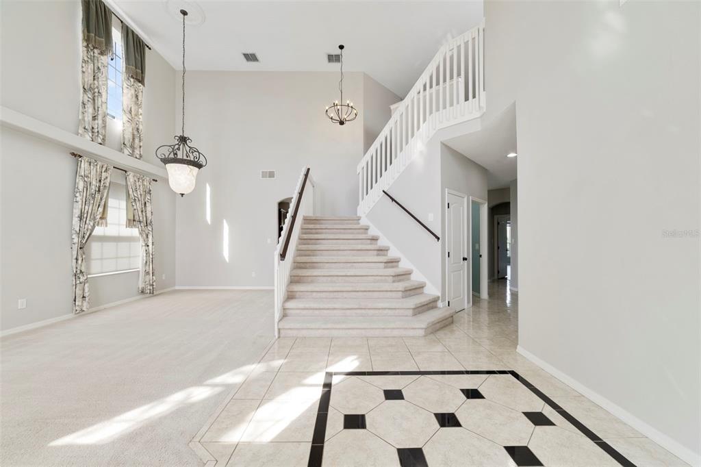 Inside, ETCHED-GLASS FRENCH DOORS open to a welcoming foyer with a SOARING CEILING and decorative tile flooring, setting the stage for the generous living spaces beyond.