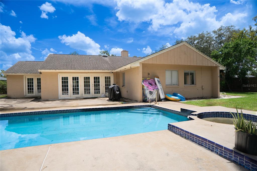 Rear exterior view of 304 Shadow Oak Drive featuring the private swimming pool and fully fenced backyard in Casselberry, Florida