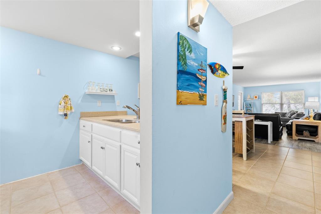 Just inside the entry, the kitchen opens toward the dining and living areas, creating a natural connection through the main living space, with tile flooring, light cabinetry and a double-basin sink.