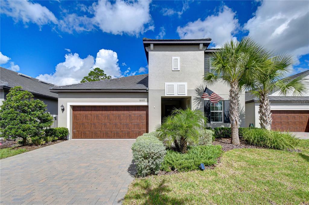 Welcoming front elevation showcasing an elegant stone entryway, manicured lawn, and beautiful palm trees.