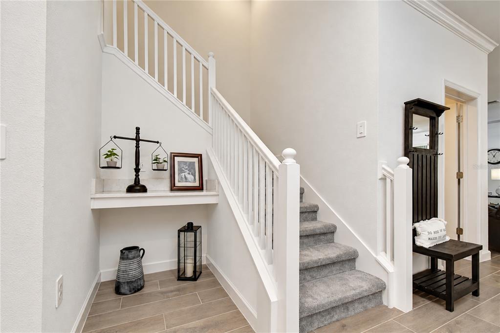 ight entry area featuring a carpeted staircase, durable tile floors, and built-in architectural accent space.