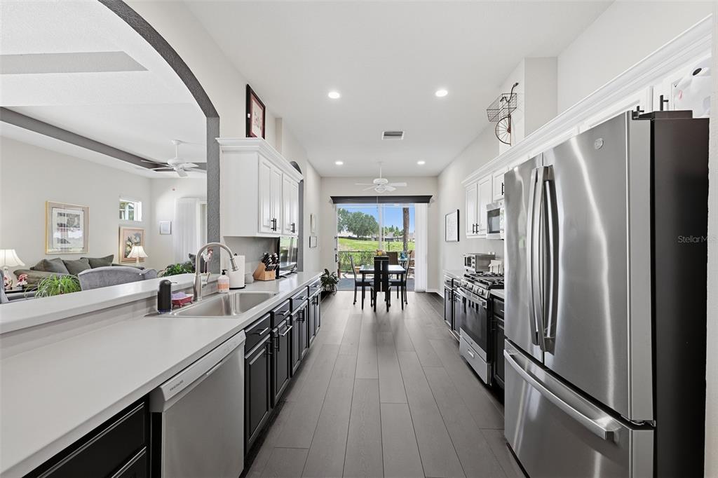CHEFS KITCHEN WITH PLENTY OF COUNTER AND CABINET SPACE WITH GAS RANGE, SINGLE DEEP SINK. BREAKFAST NOOK WITH VIEW OF THE GOLF COURSE GREEN.  FLOORING IS LPV PLANK.