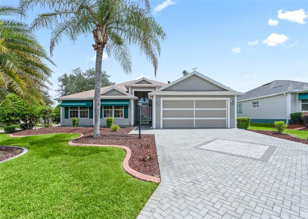 Wonderful curb appeal with a custom paver driveway, mature landscaping, palm trees and an inviting covered entry.