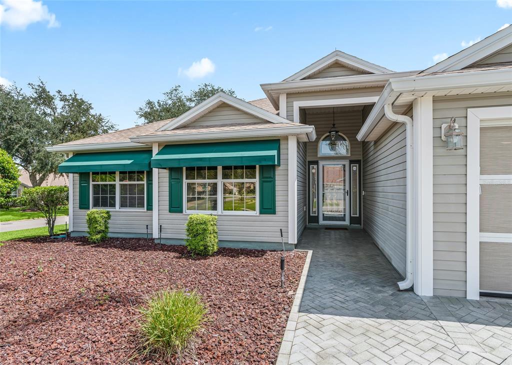 Welcoming covered front entry with paver walkway, decorative glass front door, sidelights and transom window bringing natural light into the foyer.
