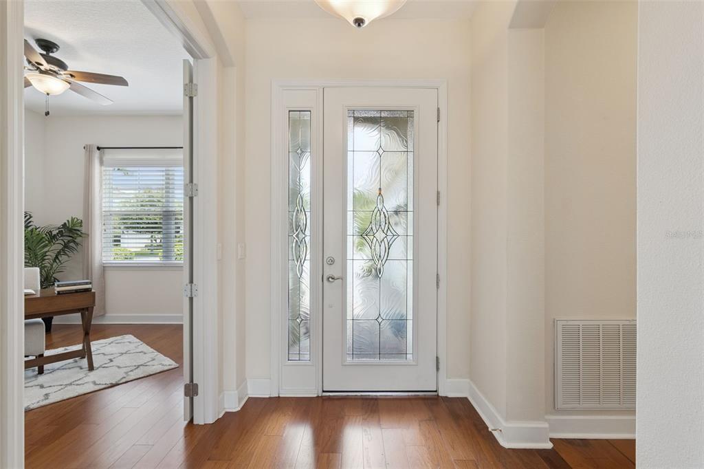 Foyer entryway w/ leaded glass door, engineered wood flooring & a tray ceiling