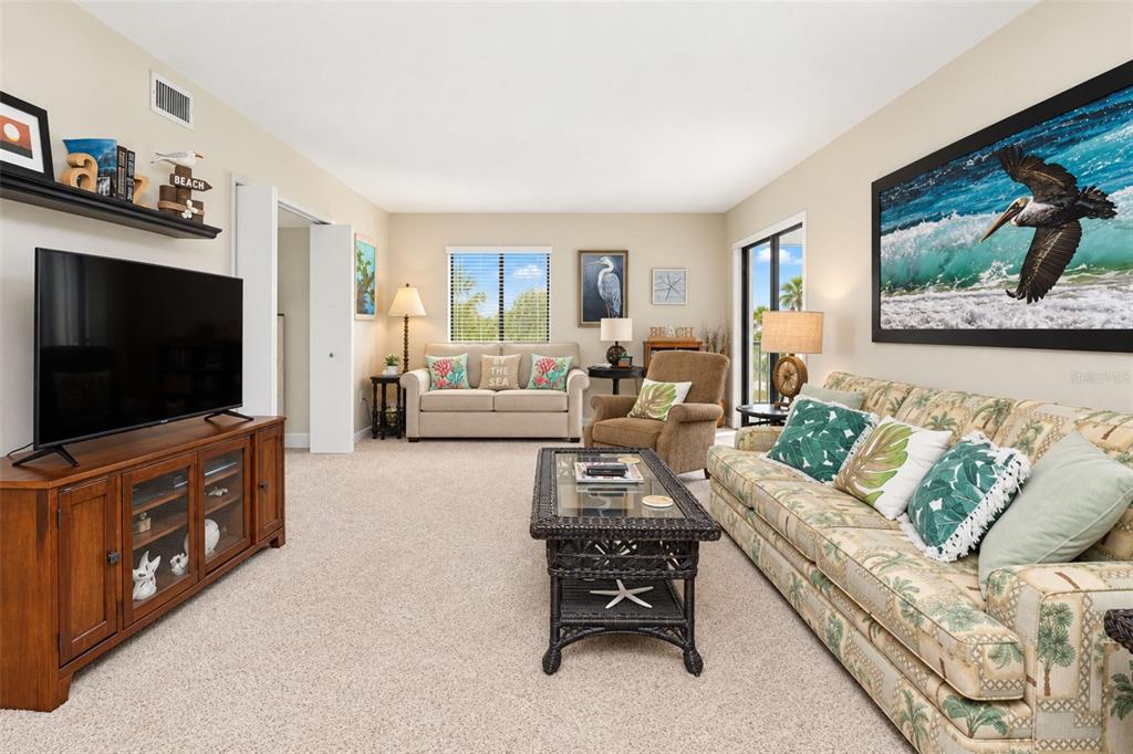 The living room has carpeted flooring and sliding glass doors to the lanai.