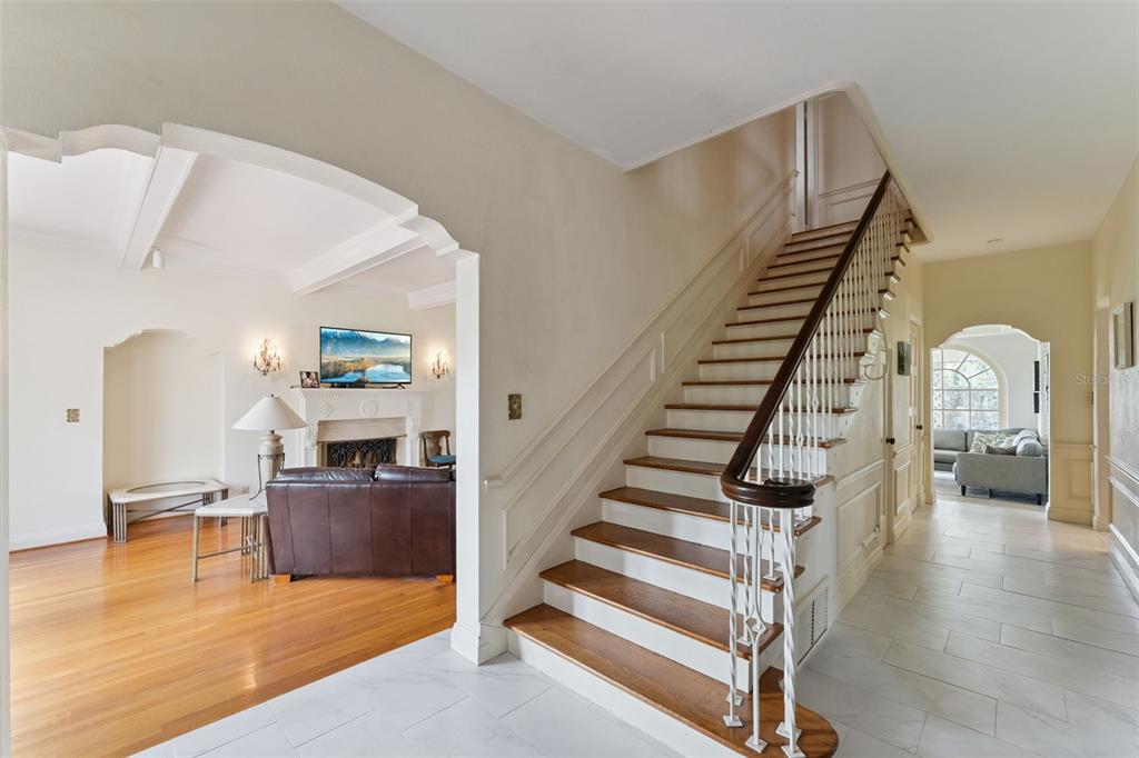 Elegant entry hall with hardwood staircase, archways framing the living room and Florida room