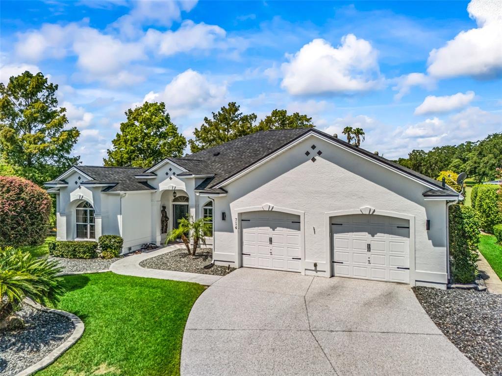Welcoming front elevation features a wide driveway, three-car garage, manicured lawn, mature landscaping, and classic Premier-home architecture.