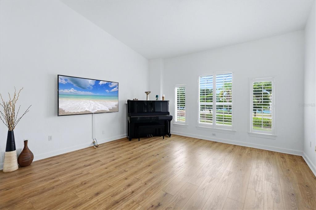 spacious family room with plantation shutters, vaulted ceilings, and items that convey